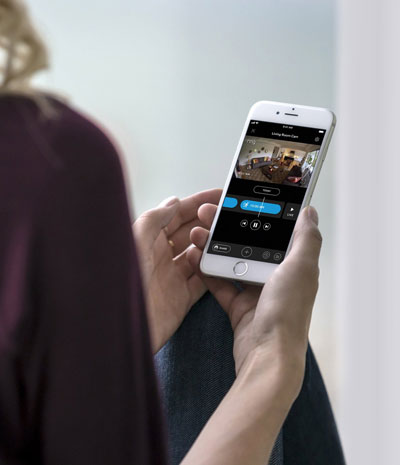 A female holding a phone, watching video footage captured by the video doorbell